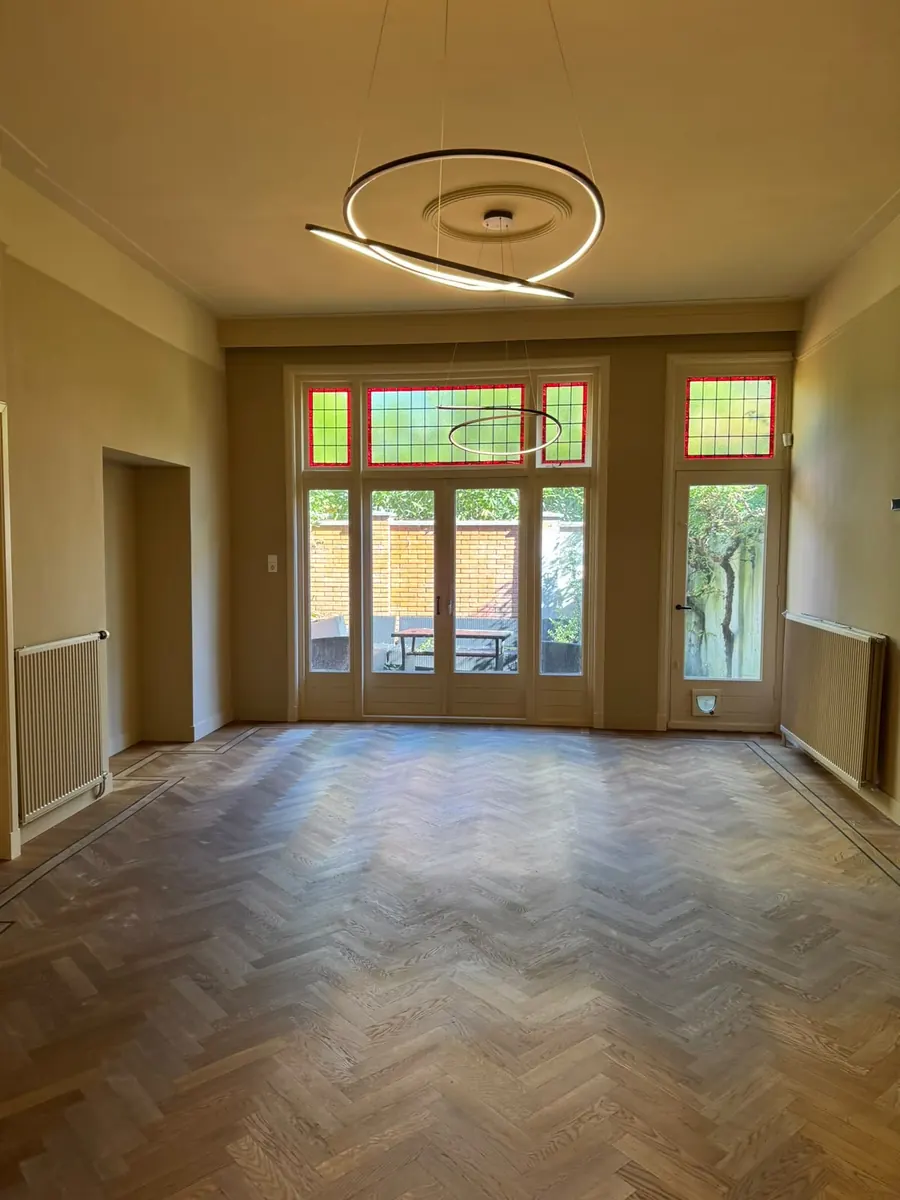 Woonkamer met glas-in-lood, plafondrozet en visgraatvloer
